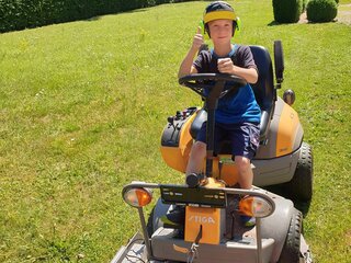 Rasenpflege: Junge auf Rasenmäher | Lobsiger Gartenbau AG