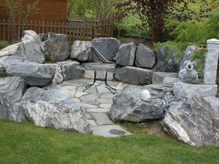 Gartensitzplatz aus grossen Steinen zum Sitzen und mit Brunnen | Lobsiger Gartenbau AG
