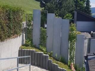 Sichtschutzwand Sichtschutzwand aus Natursteinelementen und bewachsenen Drahtgittern