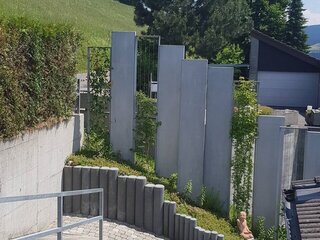 Sichtschutzwand aus Natursteinelementen und bewachsenen Drahtgittern